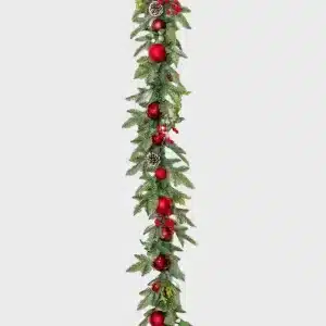 Christmas garland with baubles, pine cones, ribbons and berries