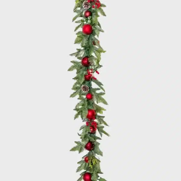 Christmas garland with baubles, pine cones, ribbons and berries