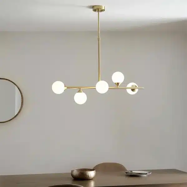 Modern satin brass linear bar pendant light with glass shades above dining table
