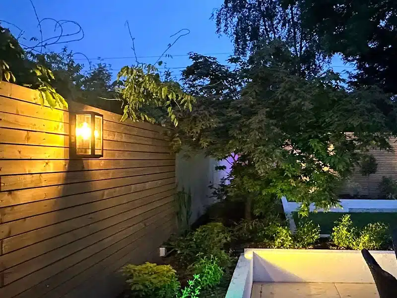 Black outdoor wall light mounted on wooden garden wall beside porch, ideal for entrance and outdoor areas