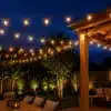 Festoon lights installed above a garden patio with warm outdoor string lights and seating area