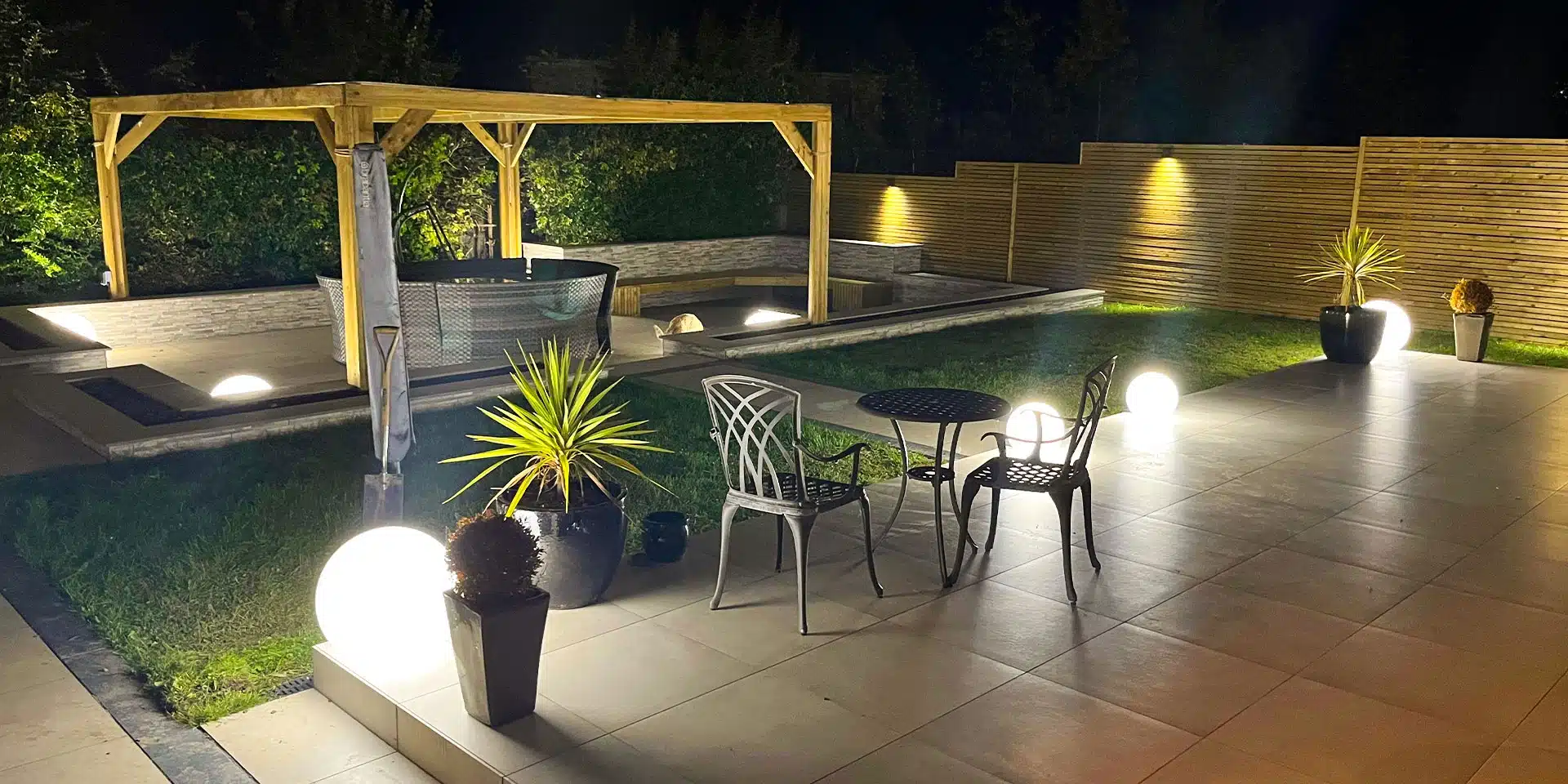 Garden lighting ideas with outdoor ball lamps, wall lights and patio seating in an Irish garden